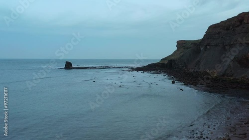 Aerial footage rising up from head height to look at the black nab at saltwick bay, yorkshire photo