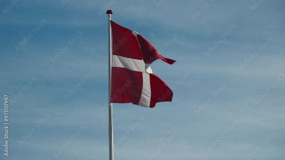Danish flag waving against a clear blue sky. Ideal for cultural and travel projects.This footage could be used in tourism videos promoting Denmark. Danish flag waving against a clear blue sky. Ideal for cultural and travel projects.This footage could be used in tourism videos promoting Denmark.