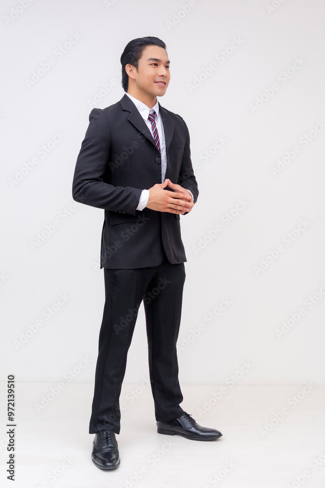 Angled view of a confident young asian businessman stands in a formal black suit and tie, exuding professionalism and focus. Hands together as if to propose. Isolated on a white background. Angled view of a confident young asian businessman stands in a formal black suit and tie, exuding professionalism and focus. Hands together as if to propose. Isolated on a white background.