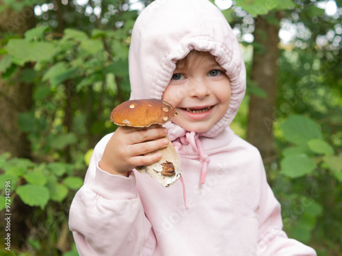 girl in the forest shows edible red mushroom