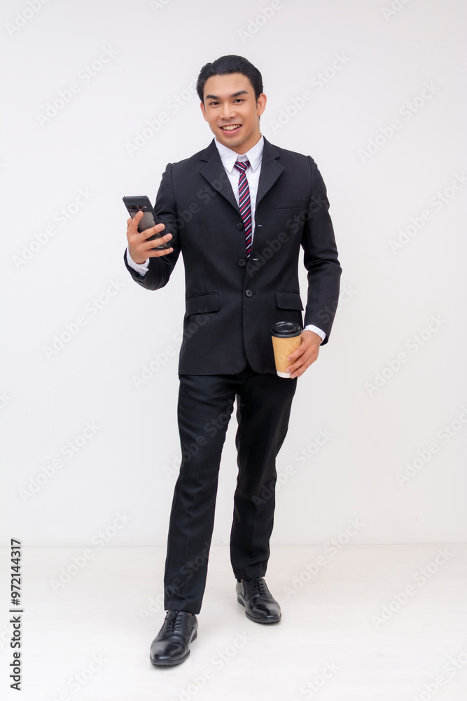 Full-body Portrait of a handsome and youthful asian businessman in a suit and tie, holding a cellphone and a cup of coffee. Isolated on a white background. Full-body Portrait of a handsome and youthful asian businessman in a suit and tie, holding a cellphone and a cup of coffee. Isolated on a white background.