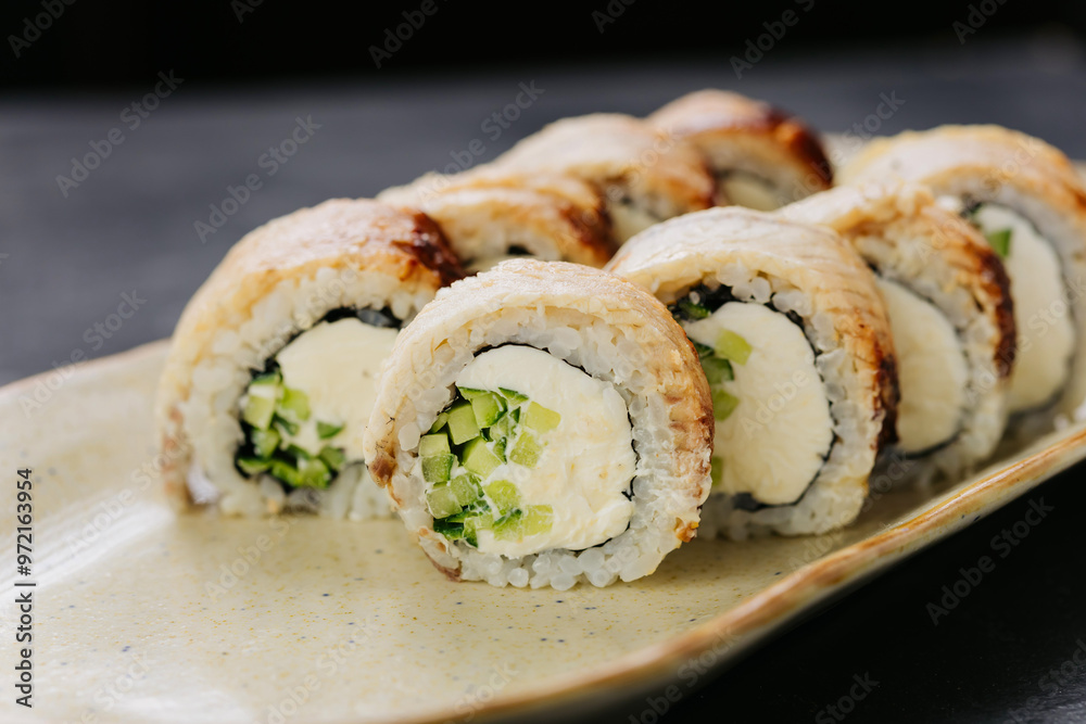 Grilled eel sushi rolls with cream cheese and cucumber on plate, perfect for Japanese cuisine lovers Grilled eel sushi rolls with cream cheese and cucumber on plate, perfect for Japanese cuisine lovers