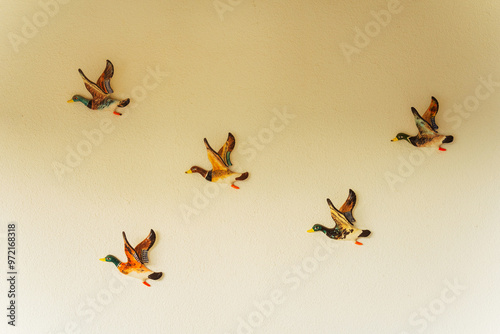 Bilde på lerret A group of four ducks is flying in a straight row on a wall