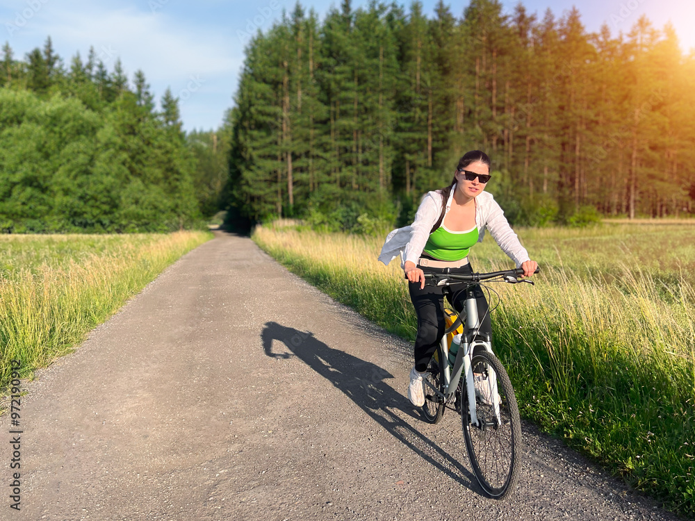 Fototapeta premium Woman riding bicycle through scenic countryside landscape