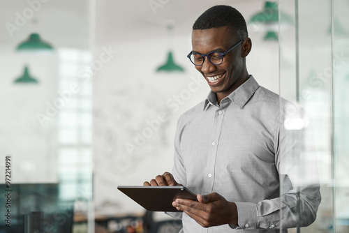 Smiling young African businessman using a digital tablet at work