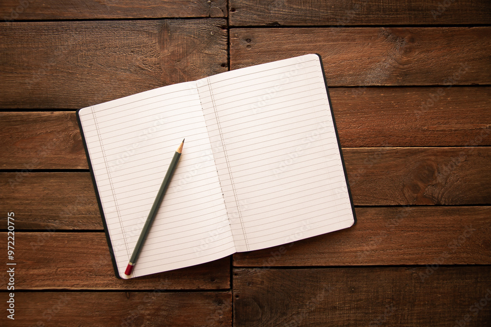 Open notebook and pencil on a rustic wooden board Open notebook and pencil on a rustic wooden board