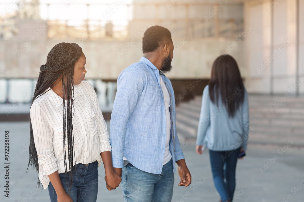 Fototapeta premium Infidelity concept. Black millennial guy distracted to another woman while walking with his girlfriend in city, selective focus