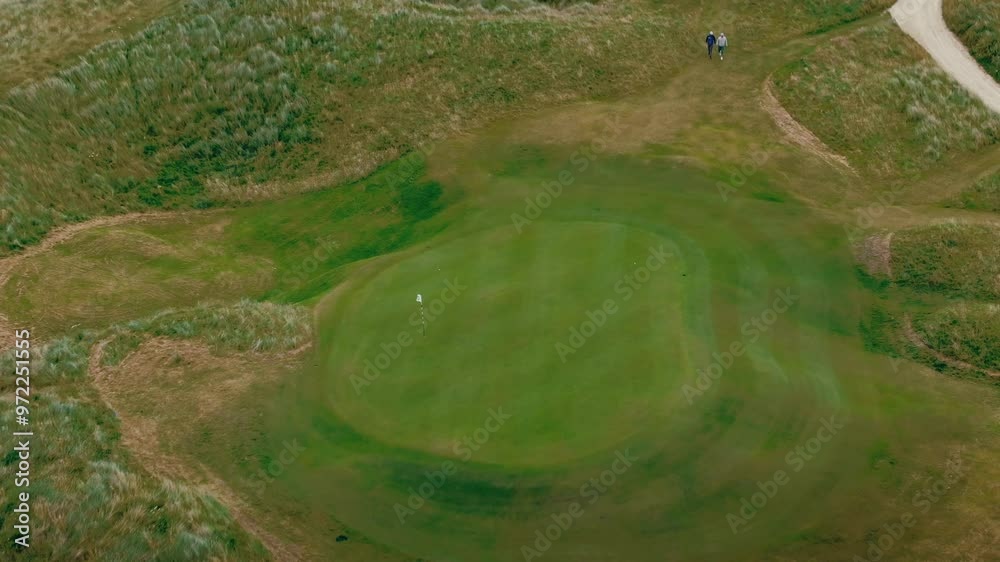 Aerial drone overhead shot of group of golfers walking off tee box to next hole on coastal green Ireland links golf course Aerial drone overhead shot of group of golfers walking off tee box to next hole on coastal green Ireland links golf course