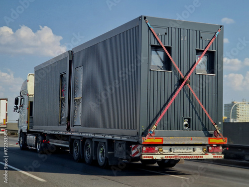 the transport of the container house is tied to the trailer with straps. construction site background or social housing. aluminum cladding and insulation photo