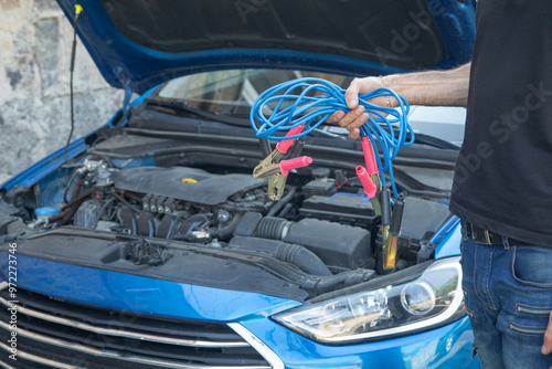 Man holding battery cable for charging the car. photo