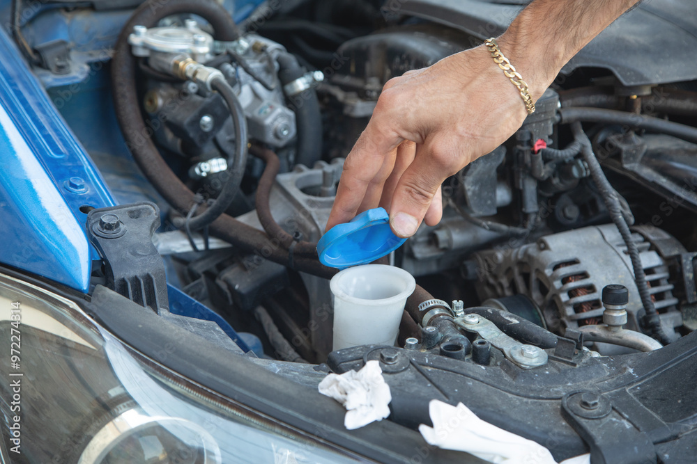 Man checking the windshield washer fluid of a car. Man checking the windshield washer fluid of a car.