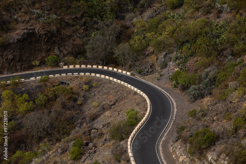 Mountain pass one-way curving road with cliffs on either side passing through the middle of the countryside.
