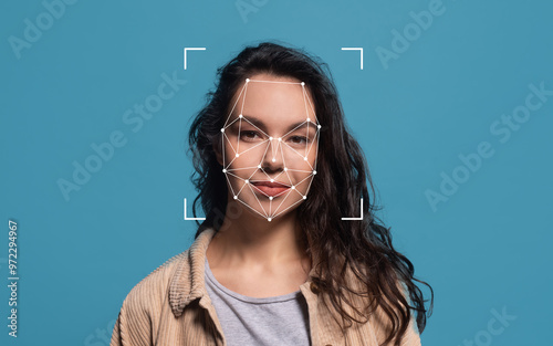 A woman with curly hair stands against a blue background, showcasing facial recognition technology with geometric outlines over her face.