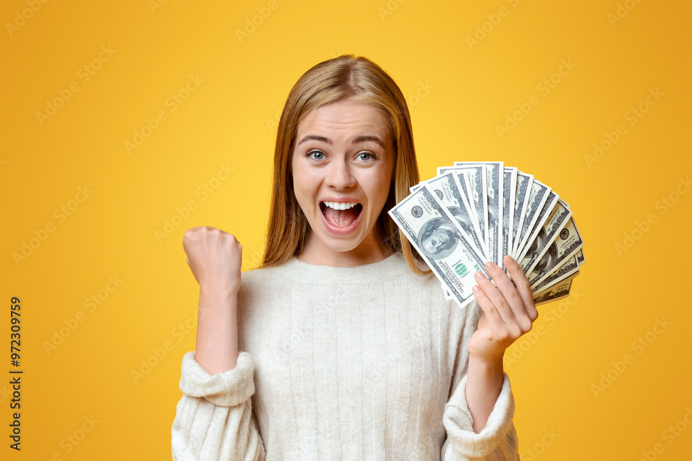 Big win. Ecstatic teen girl rejoicing success and holding lots of cash over orange background with copy space Big win. Ecstatic teen girl rejoicing success and holding lots of cash over orange background with copy space