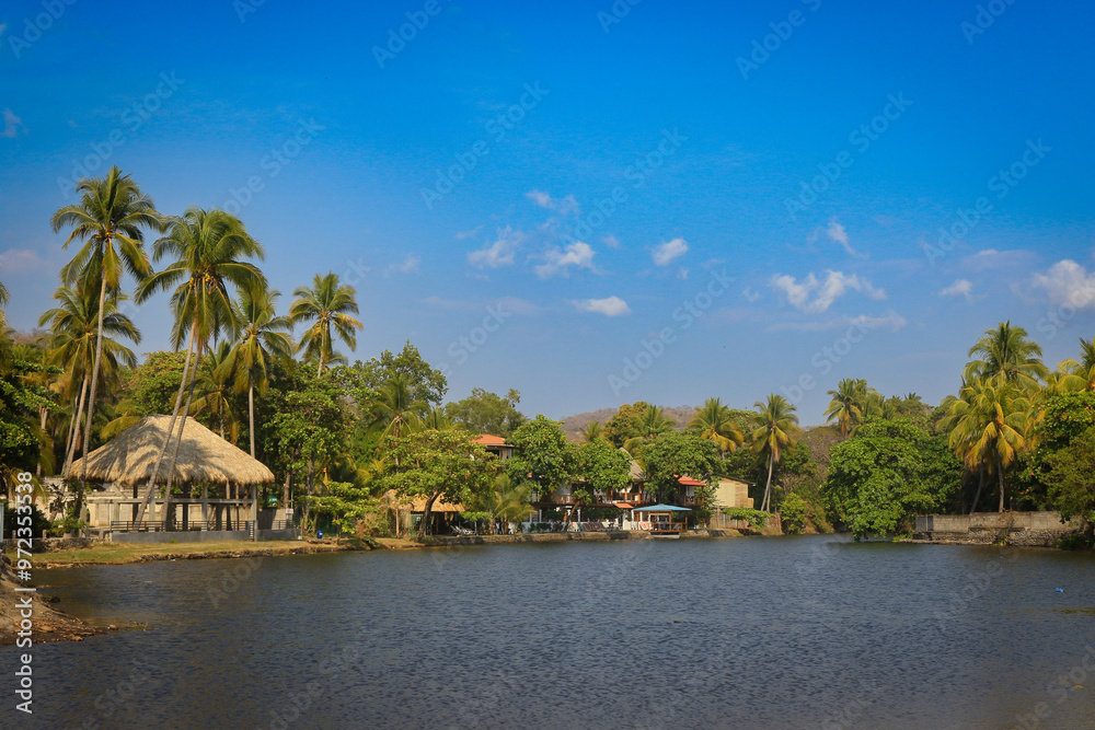 A tranquil view of El Tunco, El Salvador showcasing palm trees and calm waters at midday under a clear blue sky A tranquil view of El Tunco, El Salvador showcasing palm trees and calm waters at midday under a clear blue sky