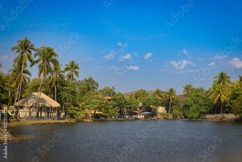 A tranquil view of El Tunco, El Salvador showcasing palm trees and calm waters at midday under a clear blue sky