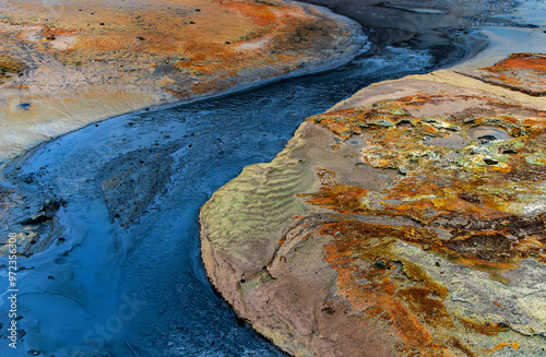 a river of dark water flows from a hot spring. photo