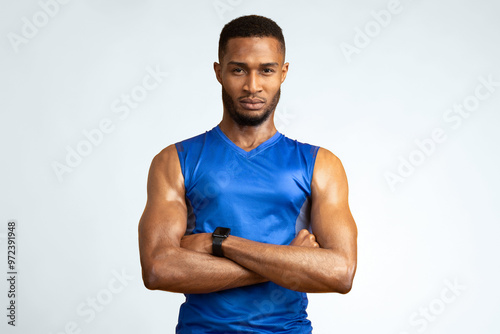 Personal Trainer. Confident black sports man standing with crossed arms isolated over yellow background. Copyspace