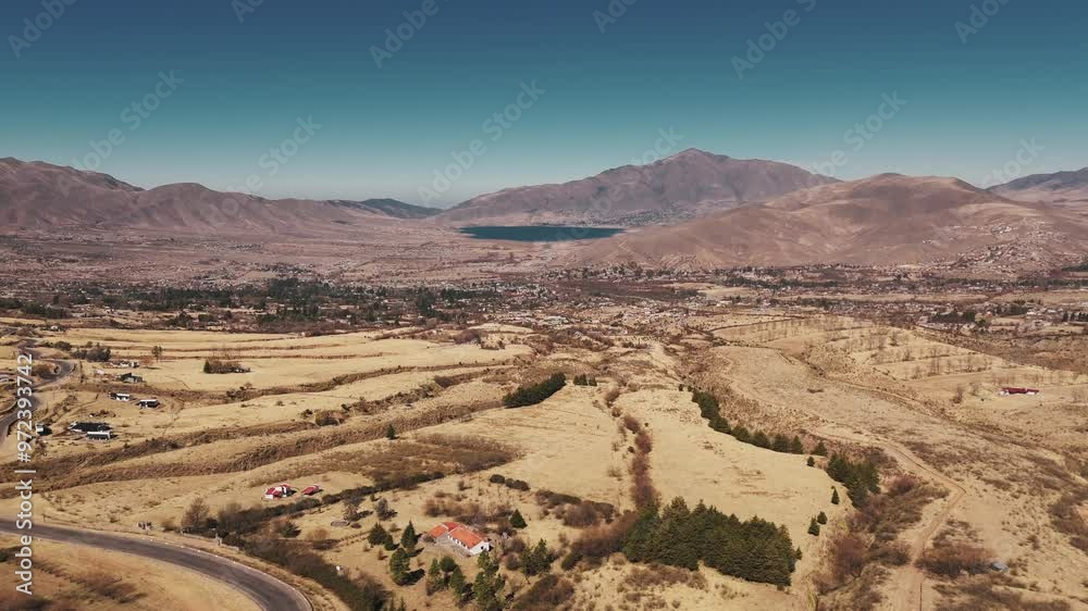 Drone ascending to reveal the magnificent Tafí del Valle, surrounded by mountains with a beautiful lake nestled in the center.