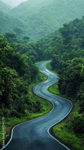 A winding road cuts through lush green hills, surrounded by dense foliage and mist, creating a tranquil and picturesque landscape