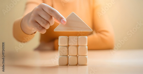 hand places a triangular block on cubes, symbolizing building a house, representing planning, stability, and real estate photo