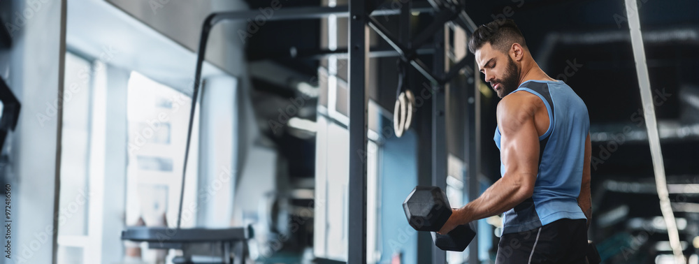 A man focuses on lifting a dumbbell, showcasing his strength in an indoor gym setting, copy space A man focuses on lifting a dumbbell, showcasing his strength in an indoor gym setting, copy space
