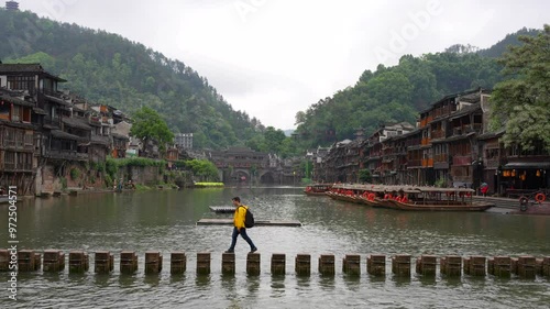 Man crossing Stepping Stone bridge over Tuojiang River in Fenghuang, China. Wide shot photo