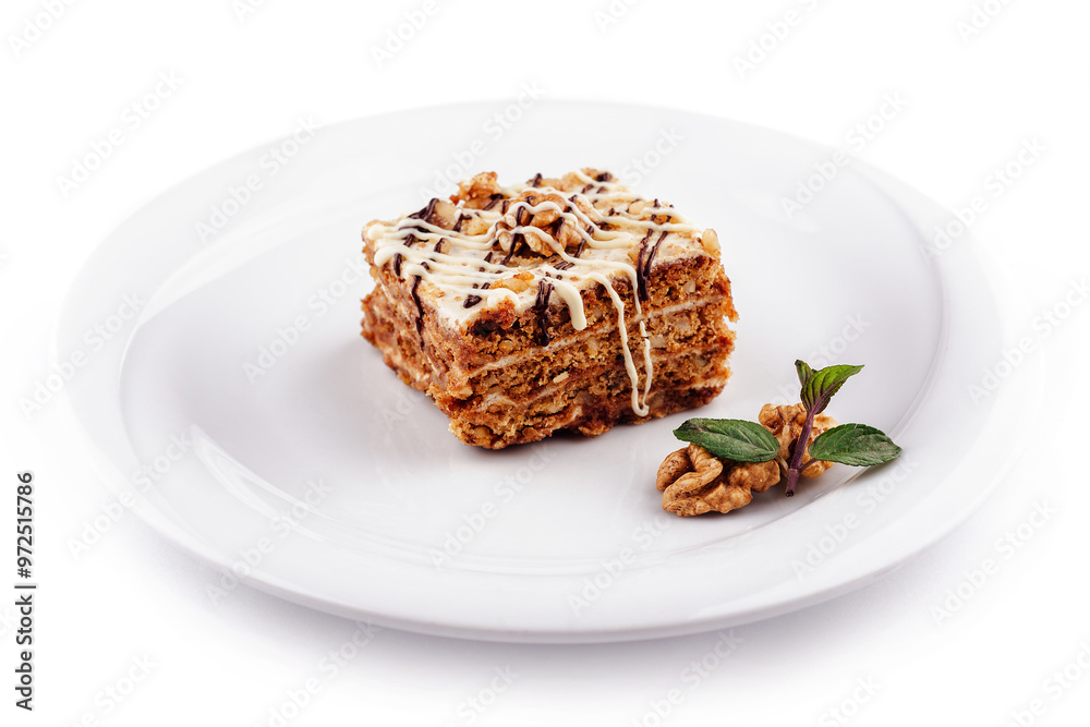 Delicious cake with walnuts and chocolate drizzle sitting on white plate