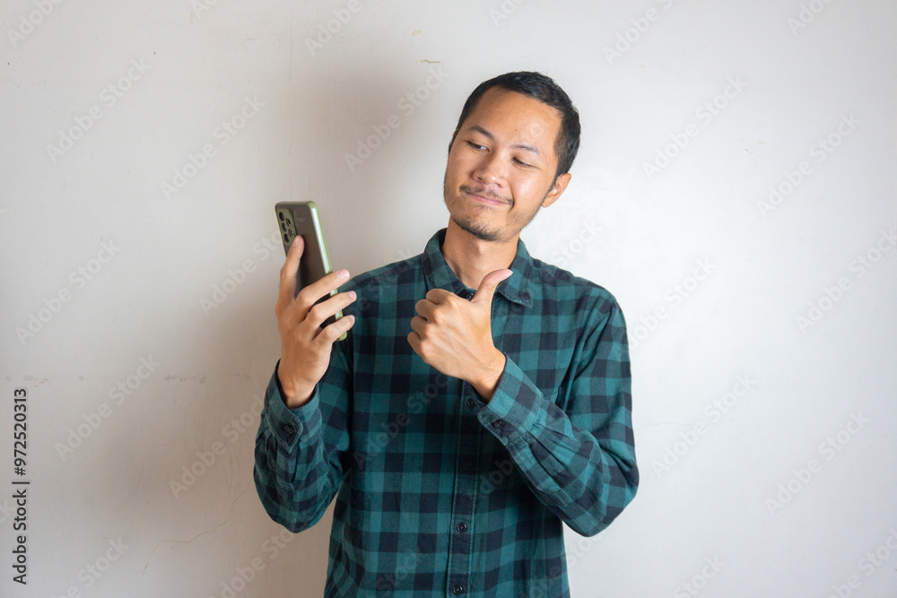 Young asian men is holding smartphone with happy expression in isolated white background Young asian men is holding smartphone with happy expression in isolated white background