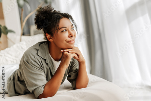 Принти на полотні Young woman lying on bed is daydreaming looking up away from camera