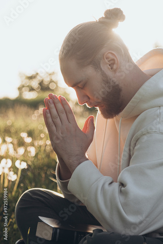 Man reading Bible and praying outdoors at sunset