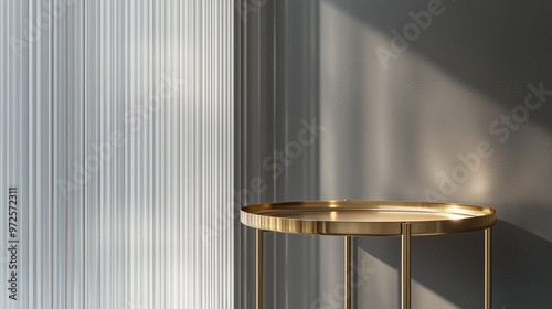 The polished gold surface of a minimalistic tray table shines brightly, set in front of a transparent vertical reeded glass panel. A light gray wall adds depth and neutrality, allowing the product's