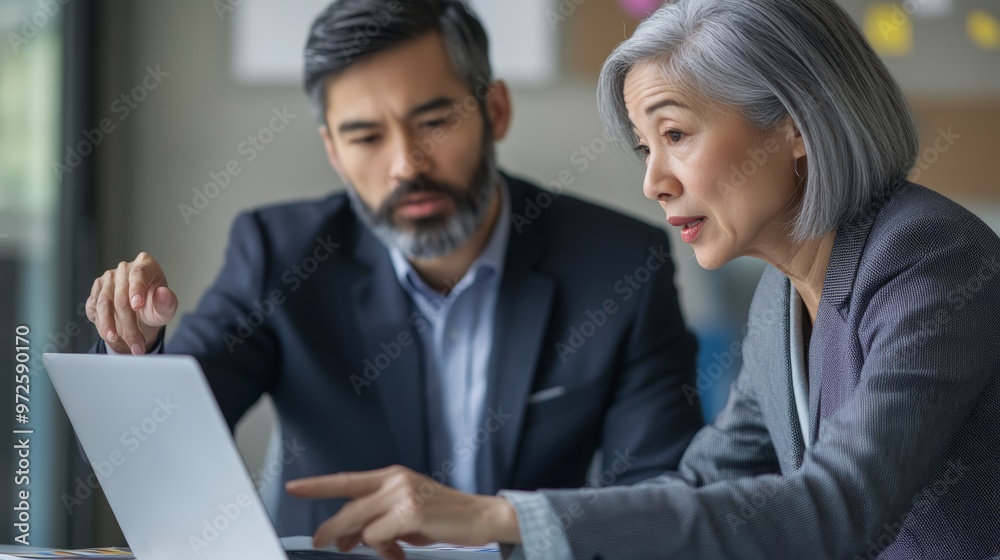 Senior businesswoman and colleague discussing work on a laptop in a modern office. Professional teamwork and mentorship. Senior businesswoman and colleague discussing work on a laptop in a modern office. Professional teamwork and mentorship.