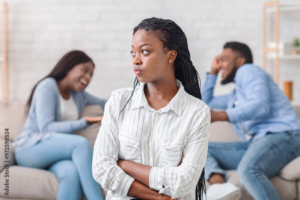 Jealousy. Black Woman Standing Offended To Her Boyfriend That Flirting With Another Girl Sitting On Couch On Background, Selective Focus Jealousy. Black Woman Standing Offended To Her Boyfriend That Flirting With Another Girl Sitting On Couch On Background, Selective Focus