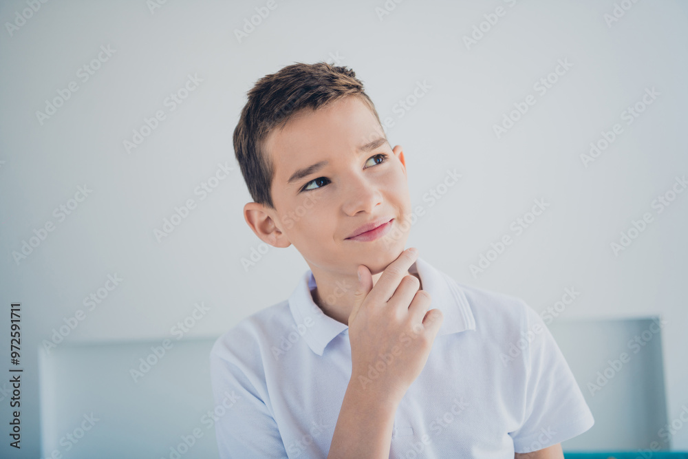 Photo of cute schoolboy hand touch chin think wear t-shirt modern interior apartment indoors Photo of cute schoolboy hand touch chin think wear t-shirt modern interior apartment indoors