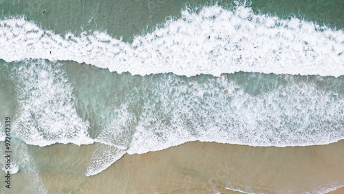         Surfers catching waves, waiting for a wave to come in the middle of the ocean near the beach during a beautiful day