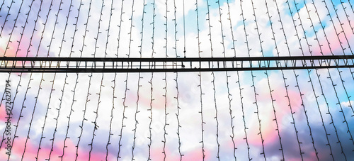 Hanging string lights against a colorful sky with pastel clouds at sunset photo