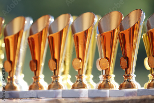 Award trophies waiting for competitors after amateur equestrian championship in row. Golden silver and bronze prizes for winners at an outdoors sport event