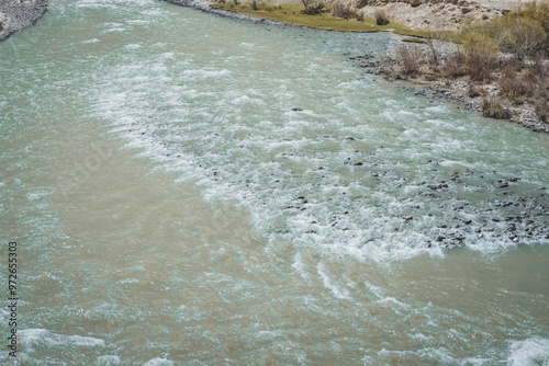 The Pamir River with blue clear glacial water flows in the valley of the Tien Shan Mountains in Tajikistan in the Pamirs, landscape for the background photo