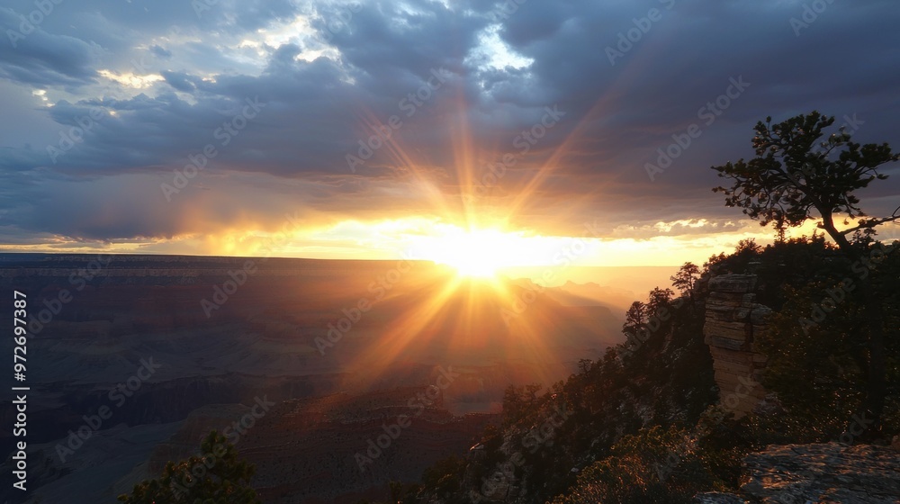 Naklejka premium Majestic Sunset Over Mountain Landscape with Sunbeams Piercing Through Dramatic Clouds
