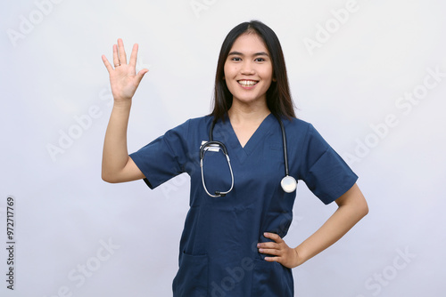 Healthcare workers and preventing virus concept. Friendly-looking smiling asian female doctor, physician in scrubs waving hand to say hi, hello, greeting patient, nice to see you