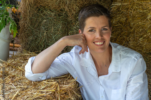 Young pretty smilig woman sitting on straw bales