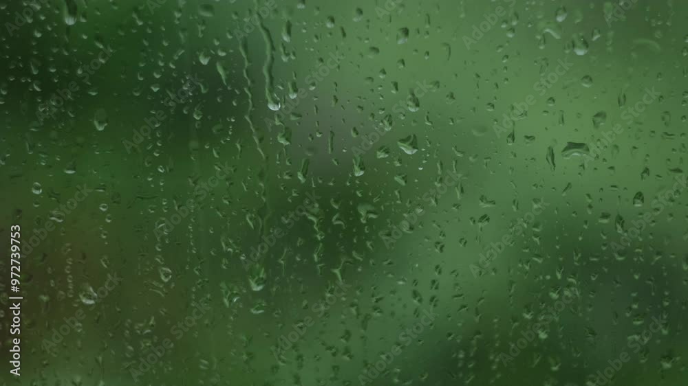 Rain days, Rain falling on window surface. Drops run off easily. Blurred green background Rain days, Rain falling on window surface. Drops run off easily. Blurred green background