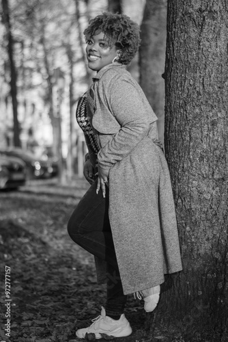 Autumn style fashion clothes worn by beautiful plus size afro Caribbean lady. Model enjoys sun during fall in urban Dutch city Den Haag vibes. Attractive confidence oozes from strong image