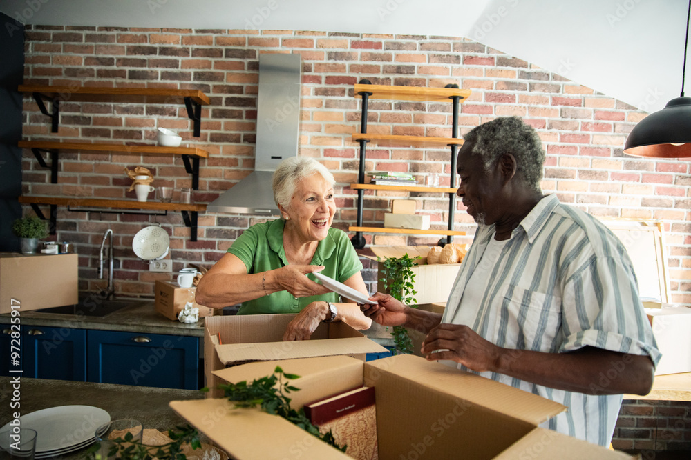 Senior couple unpacking boxes in new home kitchen Senior couple unpacking boxes in new home kitchen