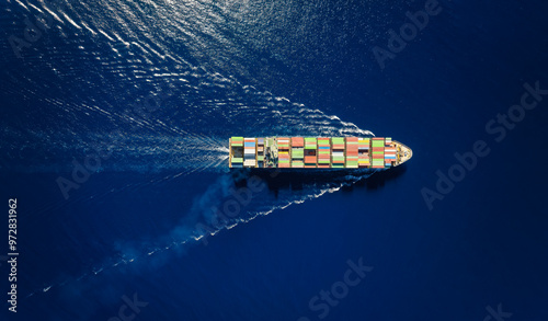 High aerial overhead view of a large industrial container cargo vessel sailing over the ocean with speed