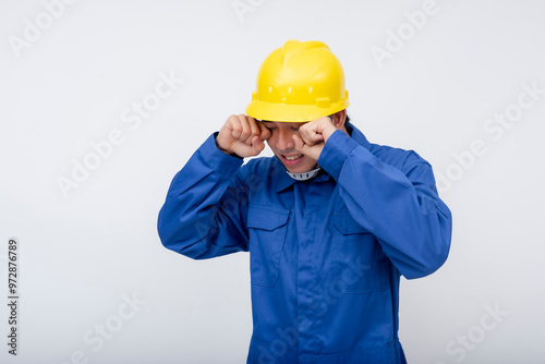 A worker rubs his eyes in fatigue, showing the effects of physical strain and tiredness. Perfect for themes of workplace exhaustion, overexertion, and job-related stress.