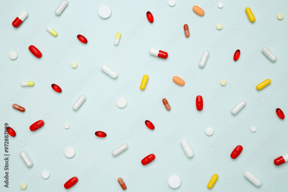 Various colorful pills and capsules scattered on a light blue background. Concept of medicine, healthcare, and pharmaceutical industry Various colorful pills and capsules scattered on a light blue background. Concept of medicine, healthcare, and pharmaceutical industry