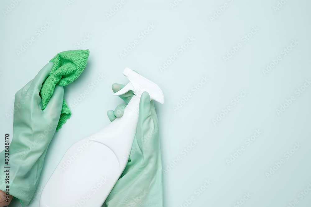 Womans hand in rubber glove holds cloths and cleaning product. House cleaning. Copy space Womans hand in rubber glove holds cloths and cleaning product. House cleaning. Copy space