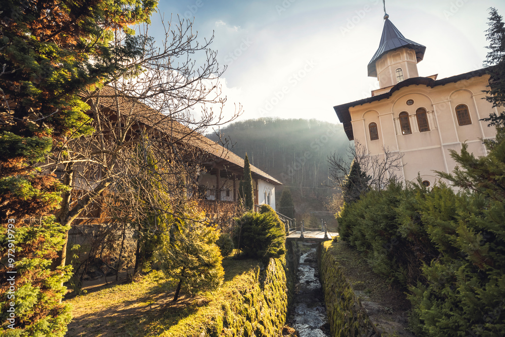 In the early morning light, a serene monastery unfolds, surrounded by lush greenery and gentle streams, offering a peaceful retreat amidst the Carpathian Mountains In the early morning light, a serene monastery unfolds, surrounded by lush greenery and gentle streams, offering a peaceful retreat amidst the Carpathian Mountains